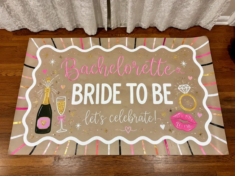 Hand-painted bachelorette banner reading Bride to Be with champagne, a ring and lips on kraft paper