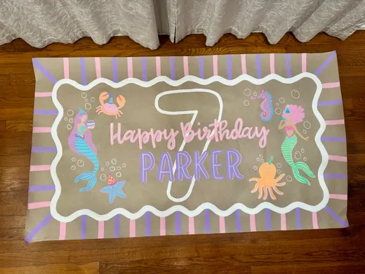 Hand-painted mermaid birthday banner reading Happy Birthday Parker on kraft paper with a wavy white border